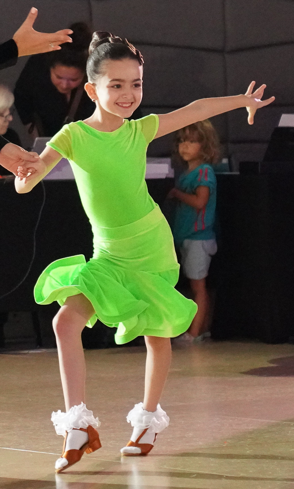 Ella Grace Helton wears a bright green dress while competing at a recent ballroom dancing competition.